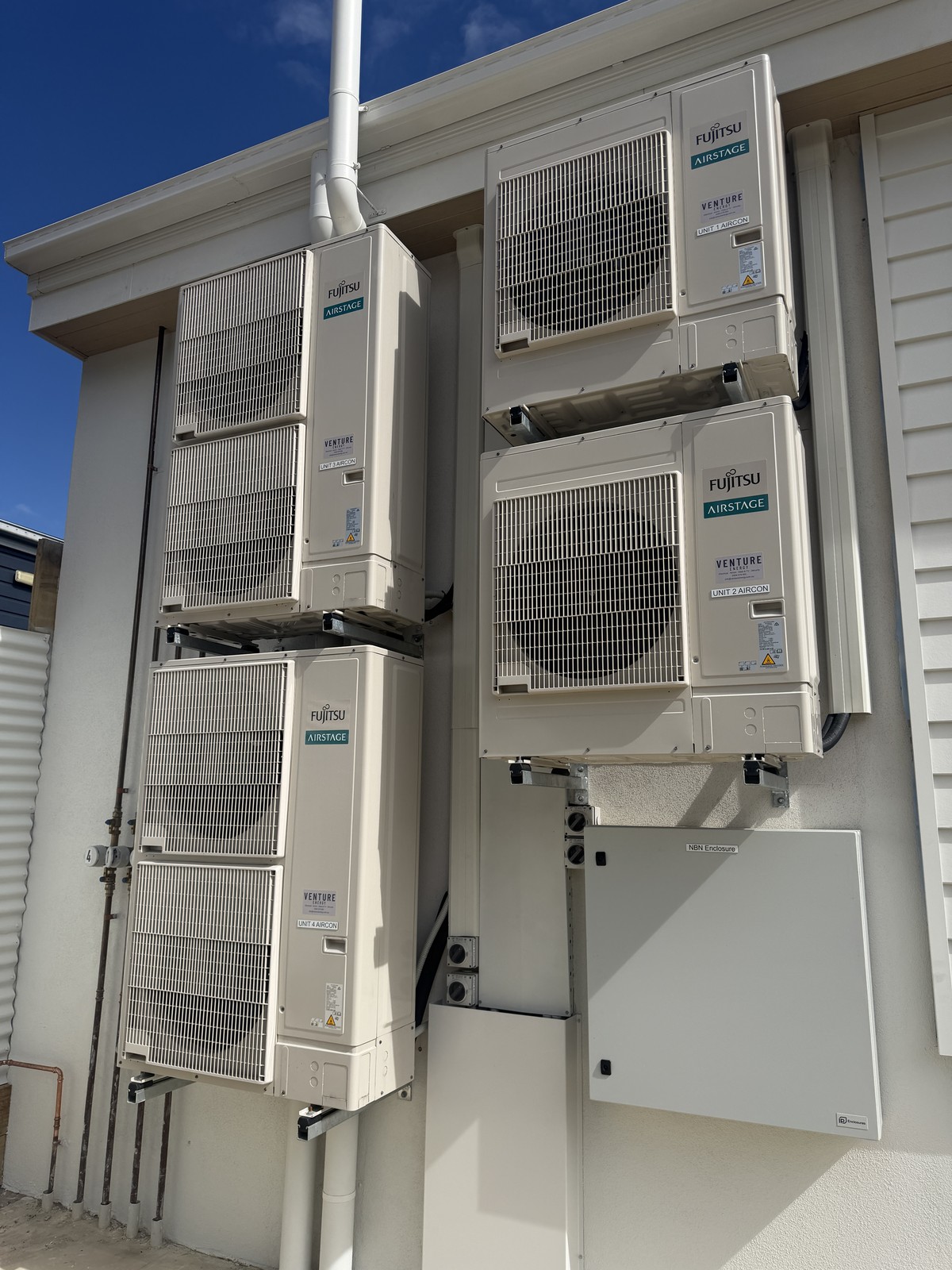 Four Fujitsu Airstage outdoor units installed and labelled by Venture Energy on a multi-unit build