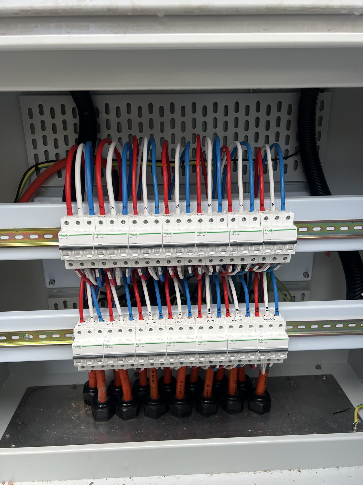 Colour-coded looped wiring across two rows of breakers in a multi-unit distribution board